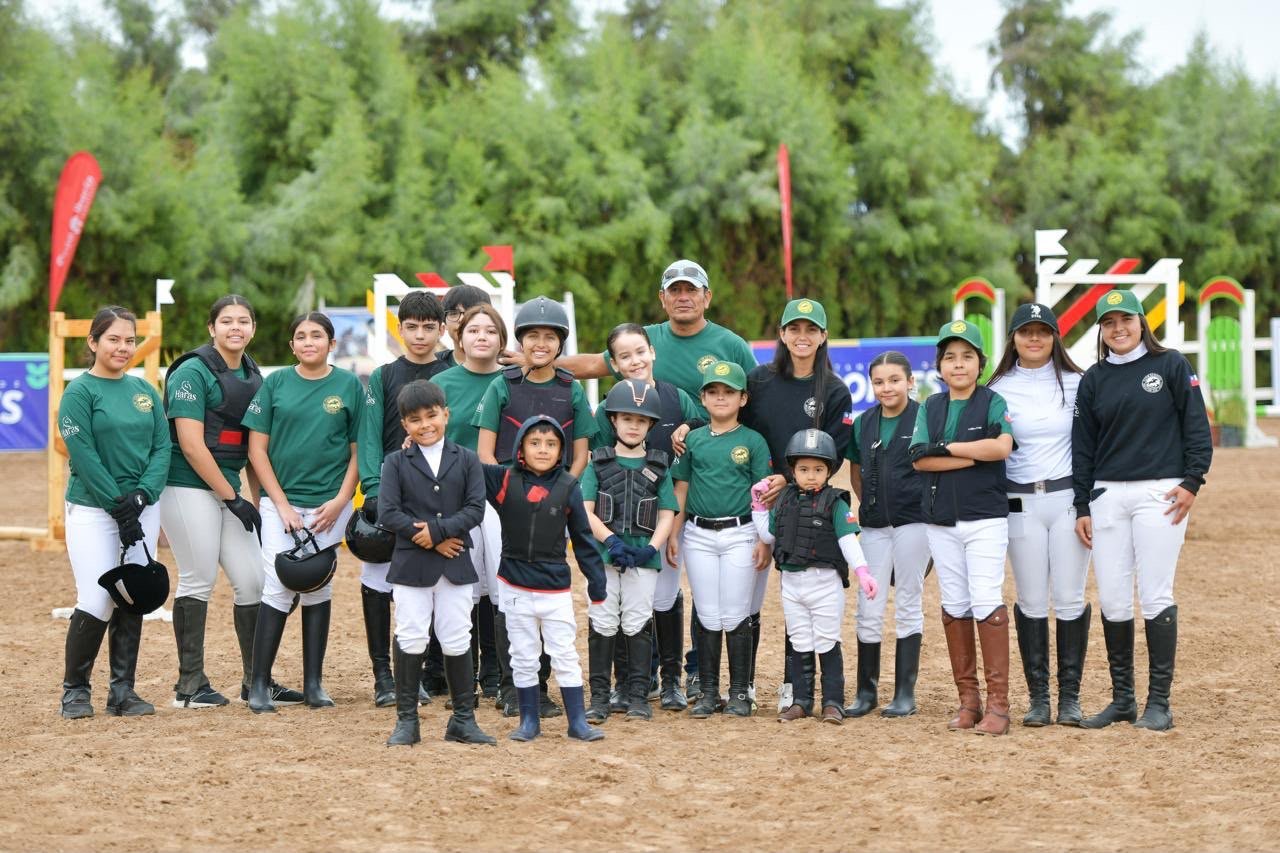 Grupo de jinetes reunidos junto a los obstáculos de una pista ecuestre